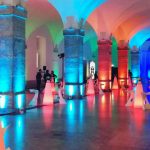 Room decorated with tables and colorful lights for an event.