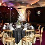 Inside a dinner event decorated in shades of gold, black and dark red.