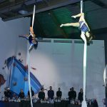 Acrobats rehearsing their numbers while holding ropes hanging from the ceiling.