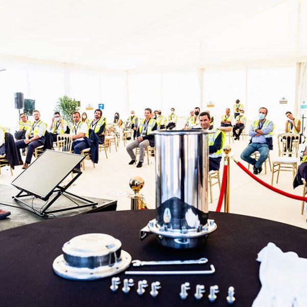 Group of people listening to a speaker talking during an event inside a tent.
